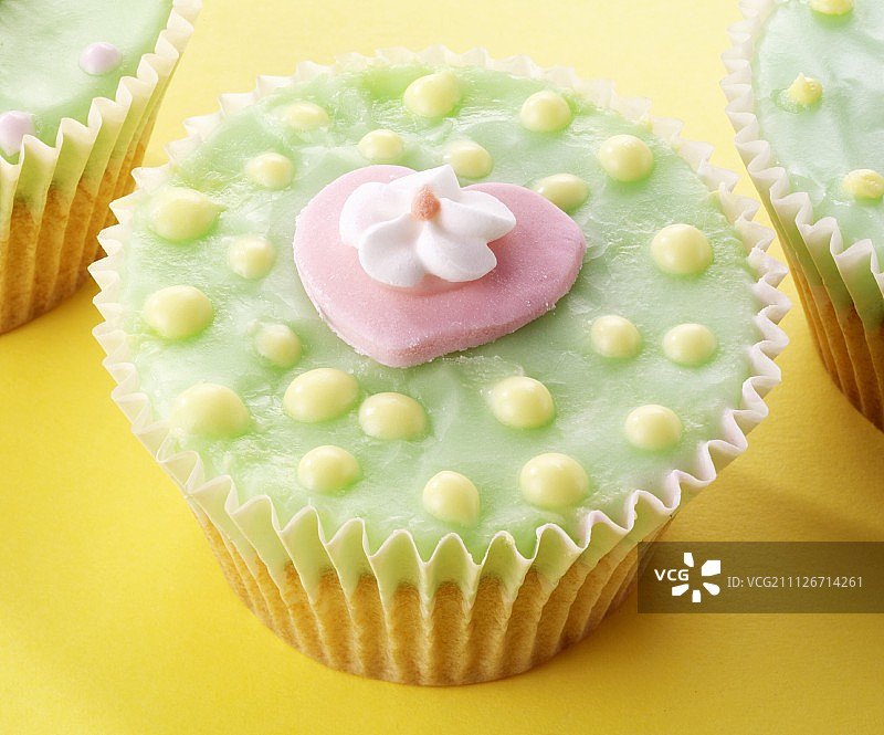 仙女蛋糕有绿色的糖衣，粉红色的心和糖花图片素材
