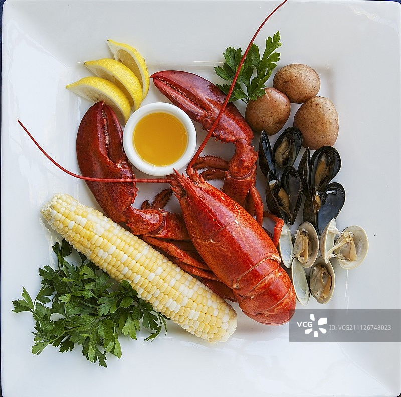 龙虾和贻贝，玉米棒，黄油酱，土豆和柠檬图片素材