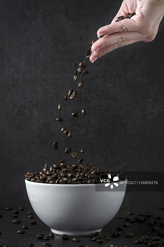 一只手把咖啡豆扔进碗里图片素材