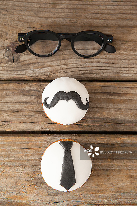 木桌上的纸杯蛋糕有胡子和领带形状的装饰图片素材