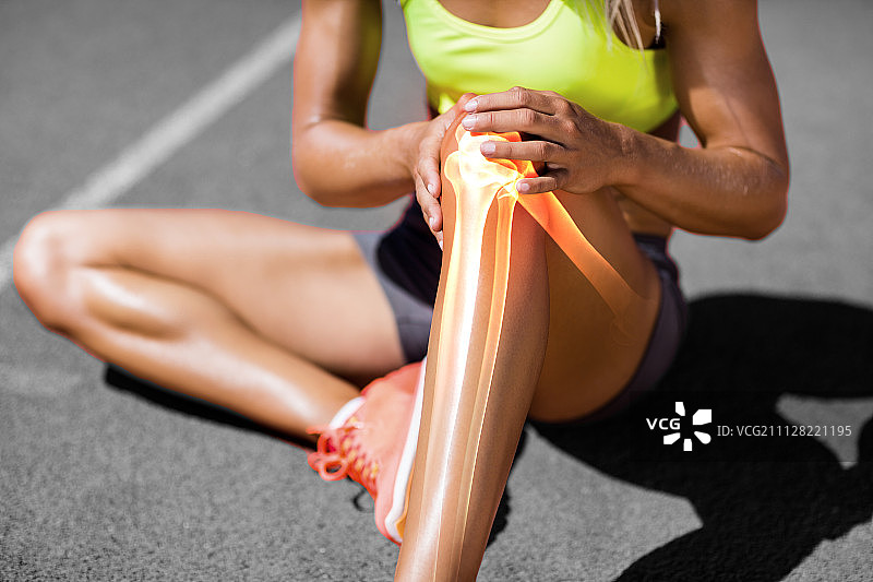 在阳光明媚的日子里，女运动员坐在赛道上时膝盖疼痛图片素材