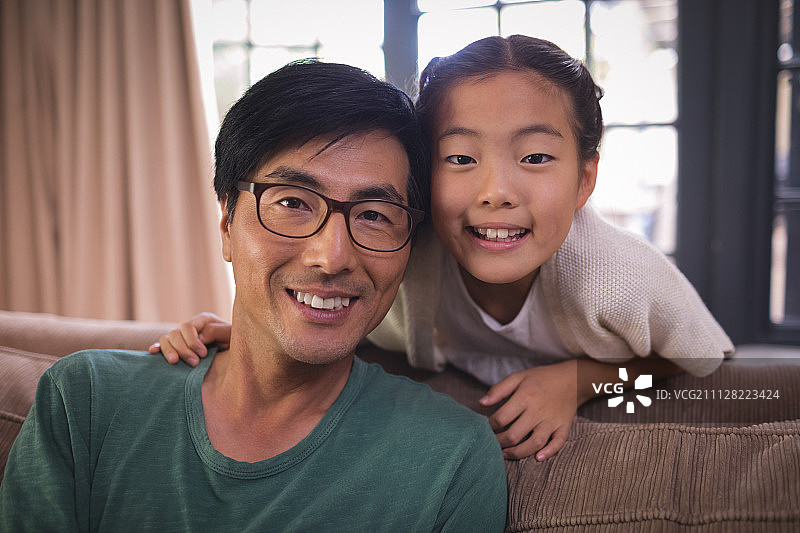 微笑的父亲和女儿一起在客厅在家里的肖像图片素材