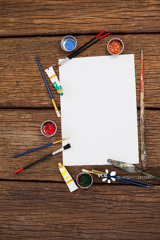 水彩颜料、画笔和白纸放在木桌上图片素材