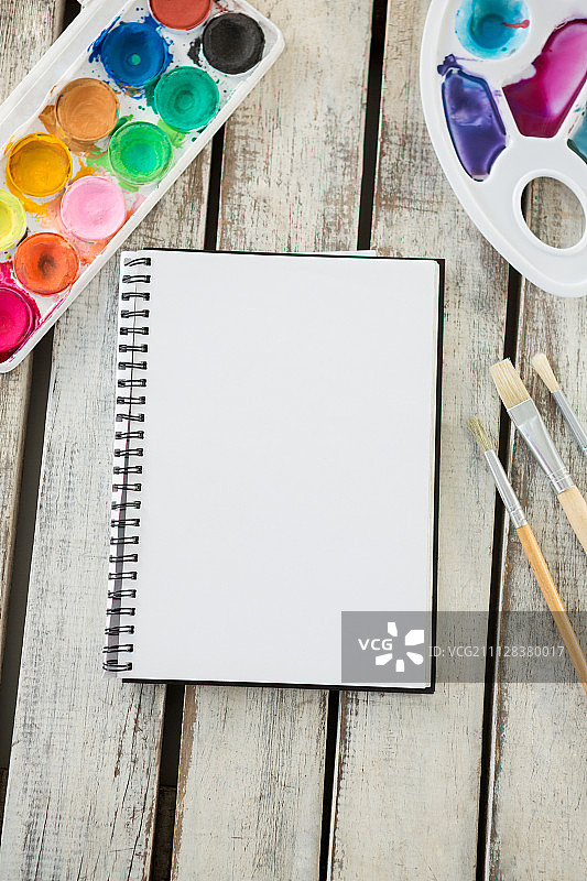 彩色调色板的特写，画笔和空白的书在木制表面图片素材