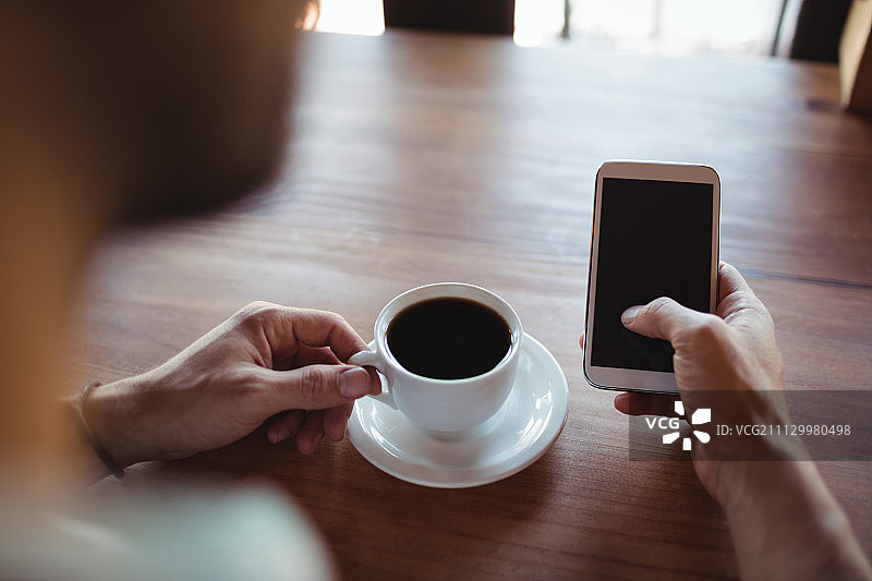 一名男子在餐厅喝咖啡时使用手机图片素材
