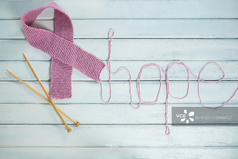 白色木桌上的粉色乳腺癌意识丝带和希望文本和钩针的俯视图图片素材