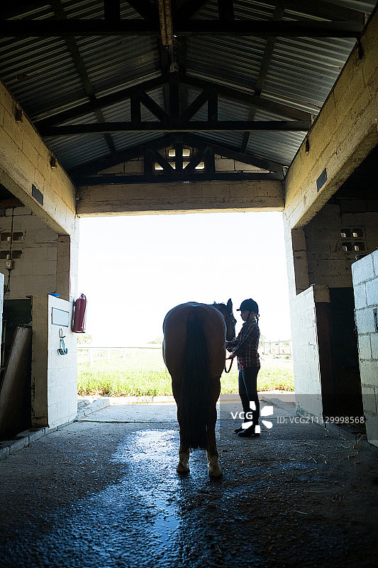 一个少女和一匹马站在马厩里图片素材