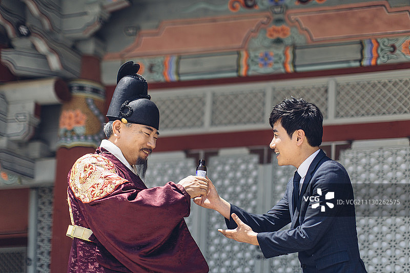 现代年轻商人给高级男子在韩国国王服装一杯饮料图片素材