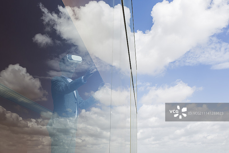 商人使用虚拟现实模拟眼镜在窗口与云反射图片素材