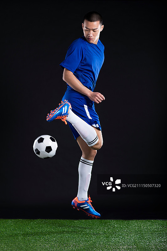 一名年轻足球运动员在草地上踢足球图片素材