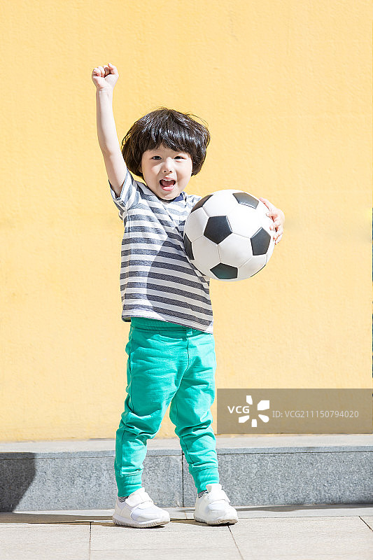 小男孩抱着足球高举手臂欢呼图片素材