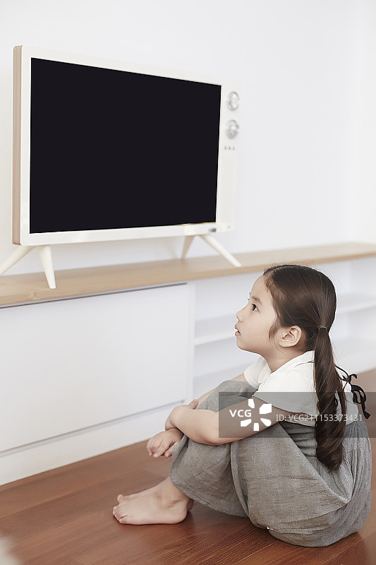 小女孩坐着看电视的照片图片素材