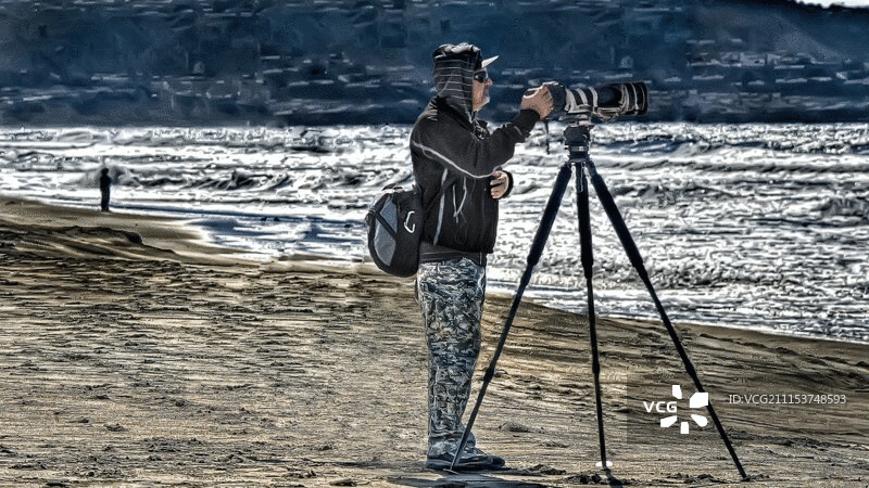 摄影师瞄准相机与长焦镜头在海滩图片素材