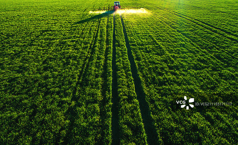 农用拖拉机在田间耕作和喷洒的鸟瞰图图片素材