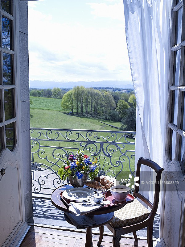 在观景阳台前的小桌子上摆着早餐用的花瓶和鲜花图片素材