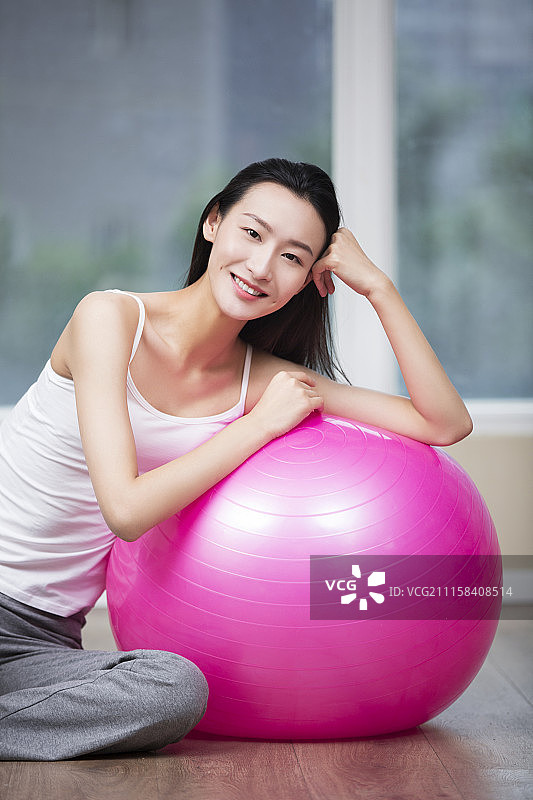 年轻女子靠着健身球上休息图片素材