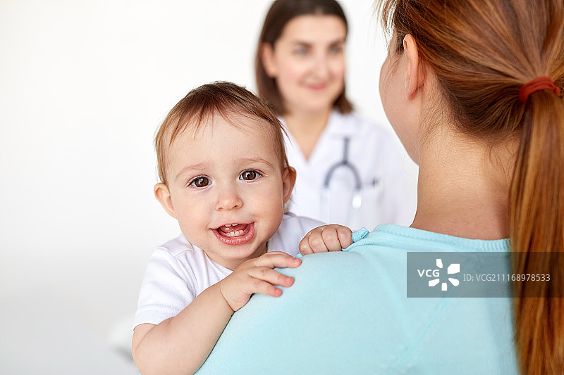 医学，保健，儿科和人的概念-近距离的快乐婴儿与母亲和医生在诊所。接近快乐的婴儿与母亲和医生图片素材