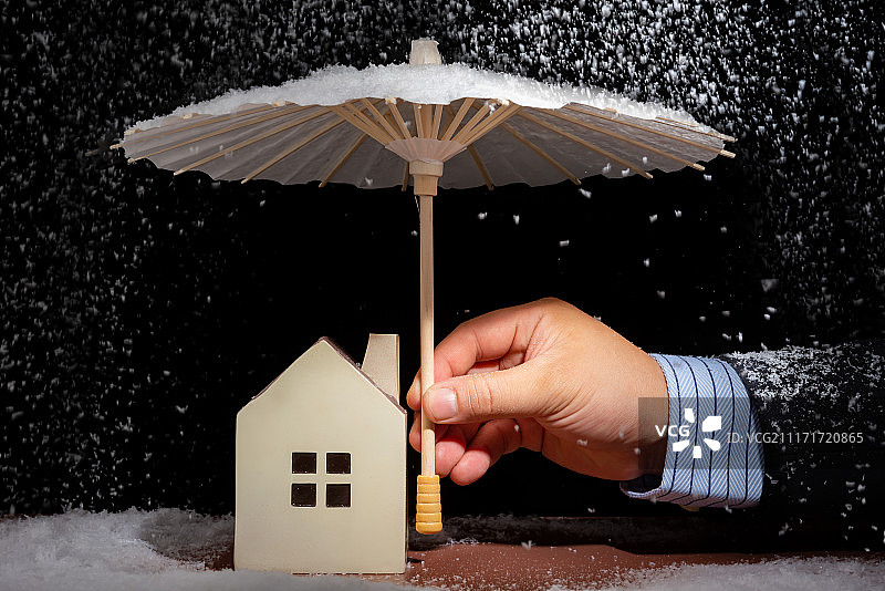 商务人士用伞给房子遮挡风雪保险保障概念图片素材
