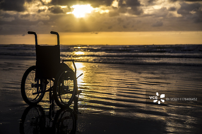 夕阳下稚气的轮椅地平线上的沙滩图片素材