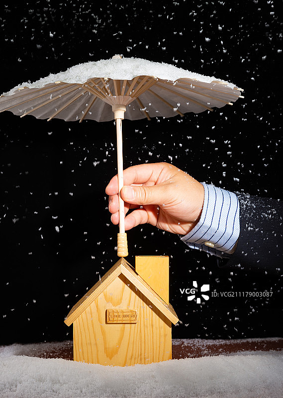 商务人士用伞给房子遮挡风雪保险保障概念竖构图图片素材
