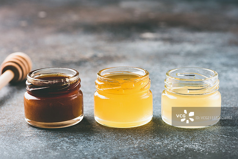 蜂蜜在小罐子和木制蜂蜜勺图片素材