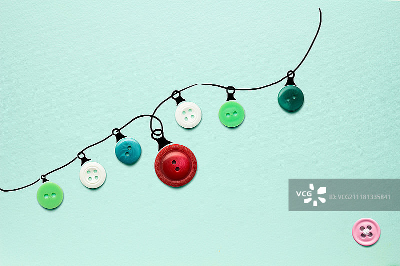 这是一张由绿色背景上的纽扣制成的圣诞彩灯的创意照片。图片素材