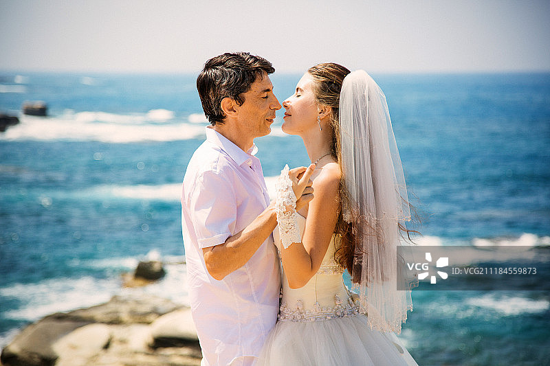 优雅微笑的新娘和新郎在海滩上散步，接吻，婚礼仪式，地中海图片素材