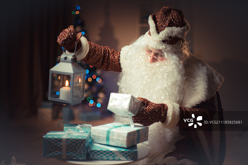 圣诞老人拿着蜡烛灯笼看着礼物。圣诞老人带来了图片素材