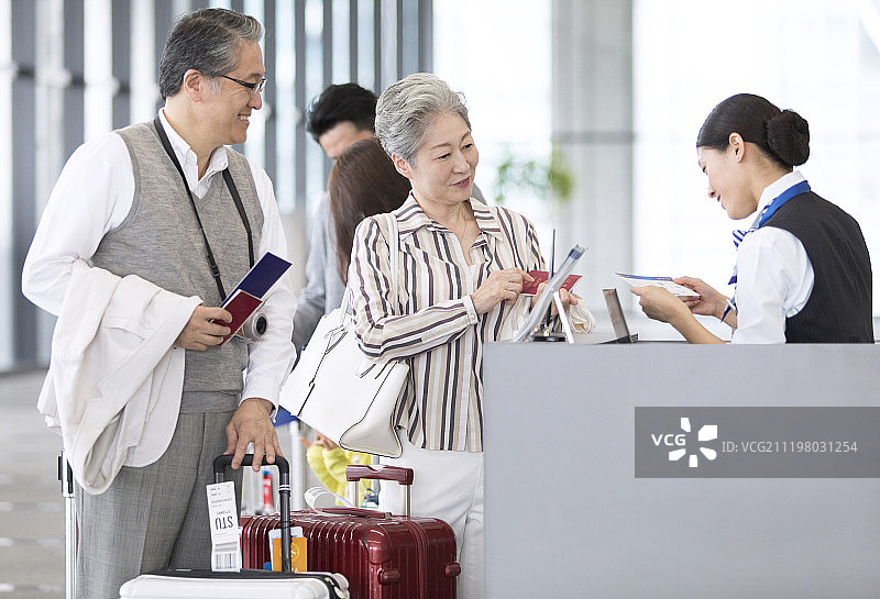 一对老年夫妇站在机场登记柜台前图片素材