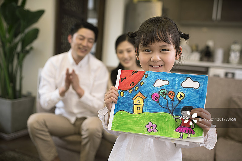 开心的小女孩展示自己画的儿童画图片素材