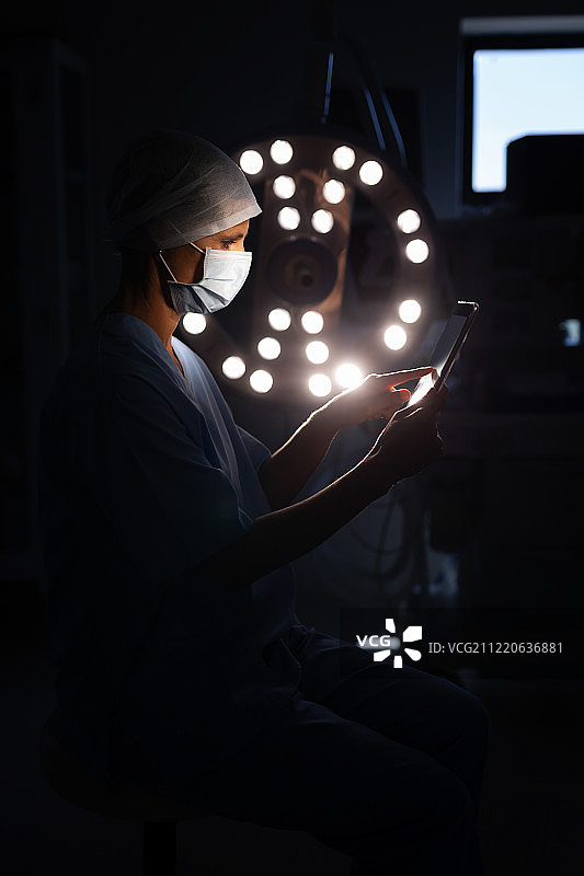 一位白种女外科医生在手术室使用数字平板电脑的侧视图图片素材