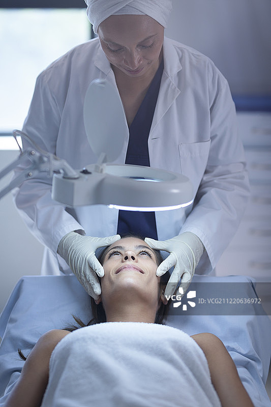 前视图的女性外科医生检查她的高加索病人在诊所整形手术图片素材