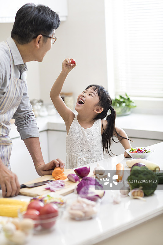 快乐小女孩和爷爷在厨房做饭图片素材