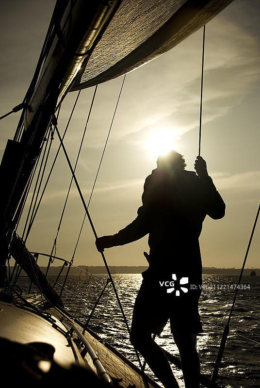 日落时海上帆船上水手的剪影图片素材