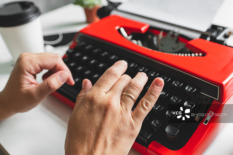 用亮红色老式打字机工作的女人图片素材