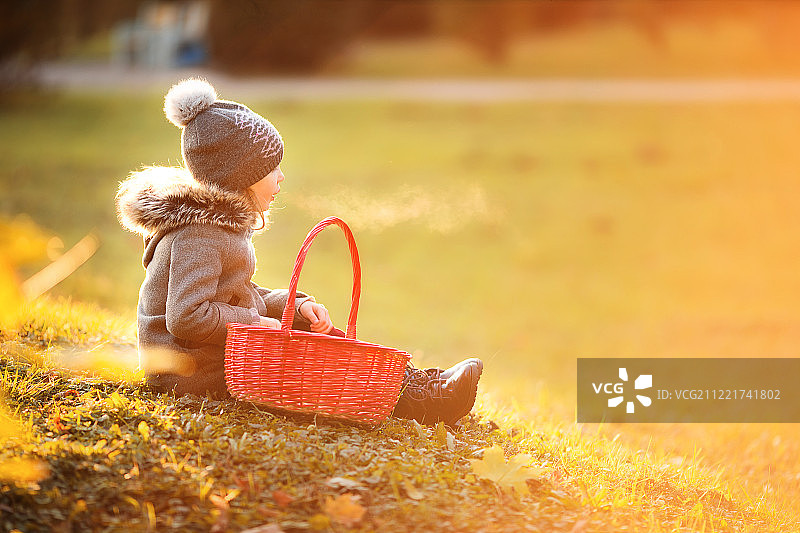 可爱的小女孩与一个篮子在寒冷的秋日户外图片素材