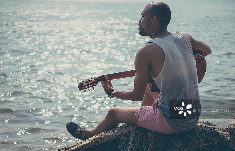 一个人坐在海边弹吉他图片素材