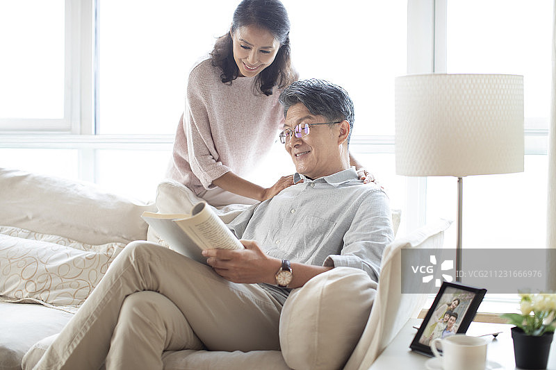 快乐的成熟夫妇在客厅看书图片素材