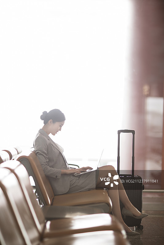 年轻商务女士在机场候机室使用笔记本电脑图片素材