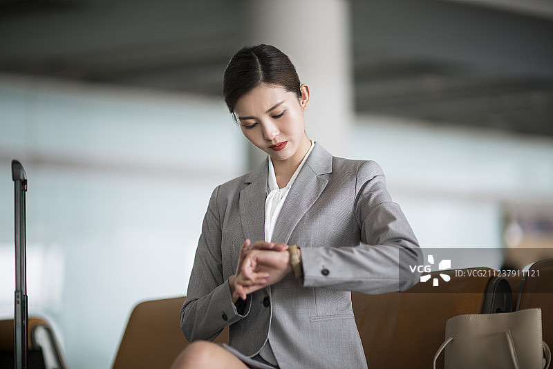 年轻商务女士在机场候机室看手表图片素材
