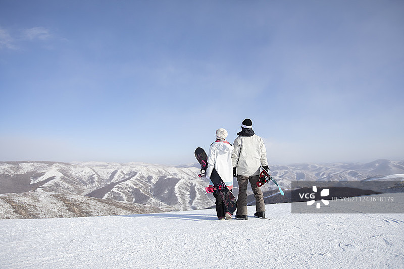 年轻情侣在滑雪场眺望远方图片素材