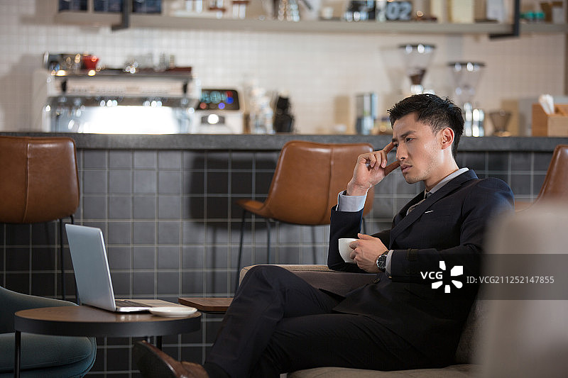 青年商务男子在咖啡馆喝咖啡使用笔记本电脑工作图片素材