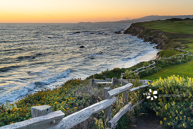 风景与篱笆沿海岸线和日落的海洋，美国加利福尼亚图片素材