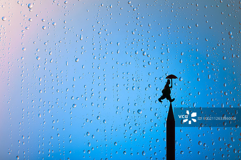 雨天水滴窗户铅笔头上撑伞的小丑图片素材