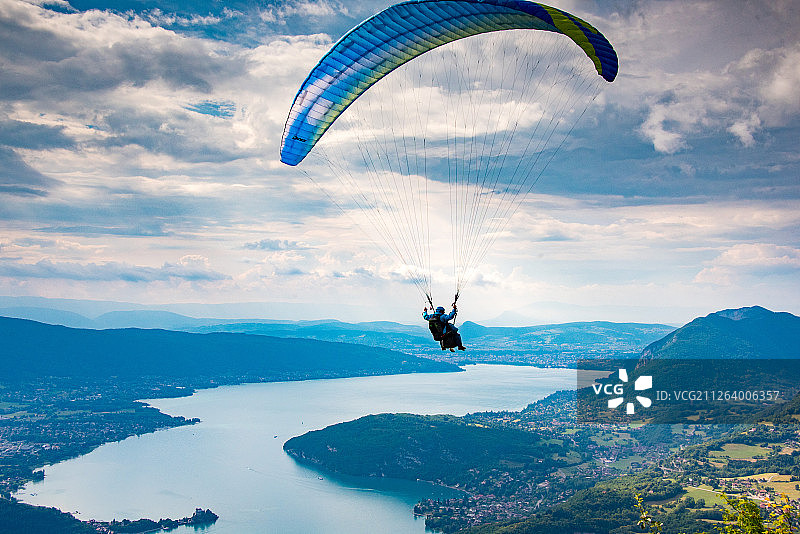 蓝天白云，湖光山色中，一个正在玩滑翔伞的极限运动爱好者图片素材