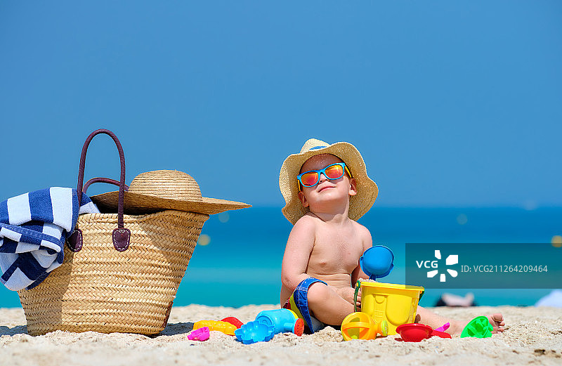 两岁蹒跚学步的男孩在海滩上玩沙滩玩具图片素材