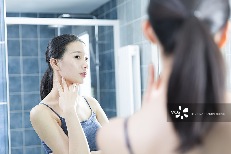 青年女子在卫生间照镜子美容护肤图片素材