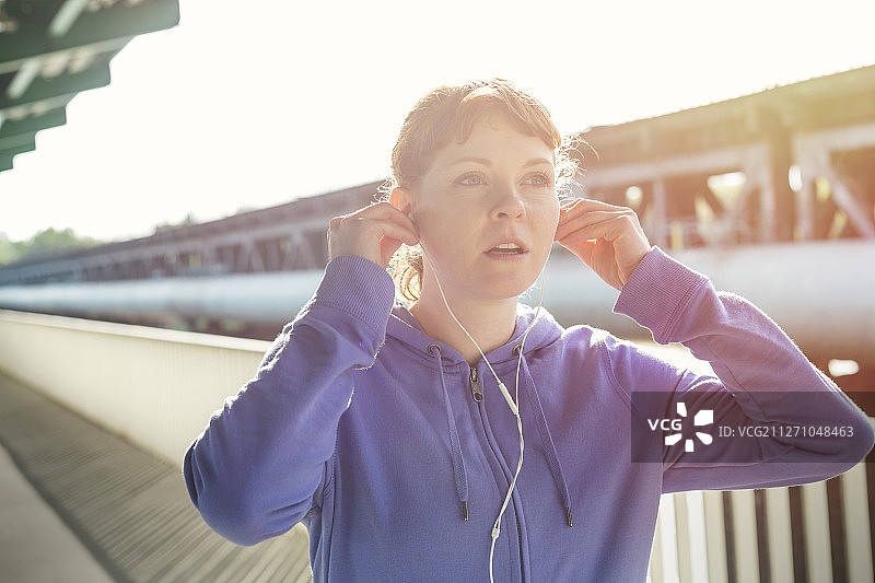 年轻女性跑步者调整耳机，听音乐图片素材