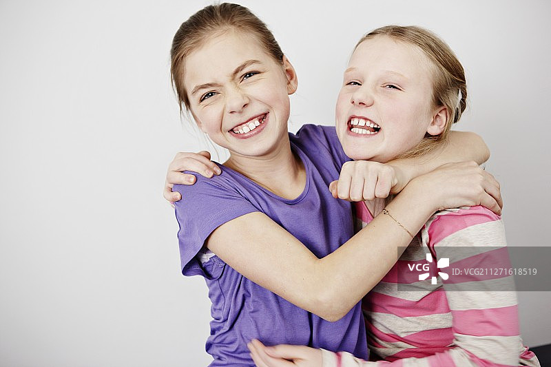 两个女孩(10-12)拥抱的工作室肖像图片素材