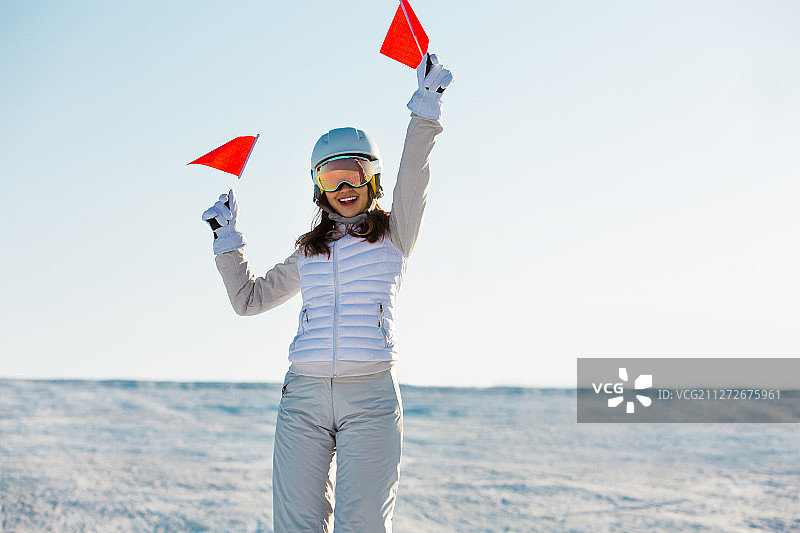 年轻女子在户外滑雪场拿着小红旗为比赛加油喝彩图片素材